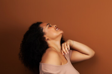 Obraz premium pretty young african american woman with curly hair posing cheerful gesturing on brown background, lifestyle people concept