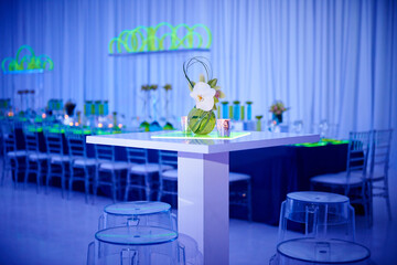 Beautiful orchid cocktail flower arrangement on lucite stools and table set up for a party in a ballroom.