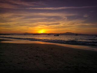 Fototapeta na wymiar Beach with an incredible sunset where you can see boats and mountains