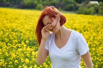 Pollen allergy, girl sneezing in a field of flowers