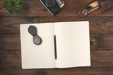 Old vintage camera with blank notepad and compas on wooden table background. Travel vacation concept. Flat lay, top view. © Konstantin Maslak