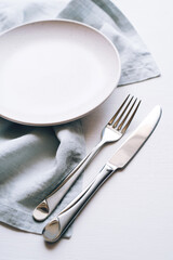 An empty plate and Cutlery on a white table. Top view.