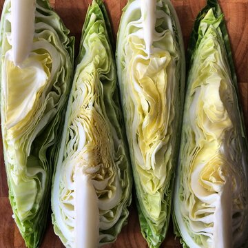 hispi pointed cabbage, sliced length-wise into quarters. arranged on a wooden chopping board