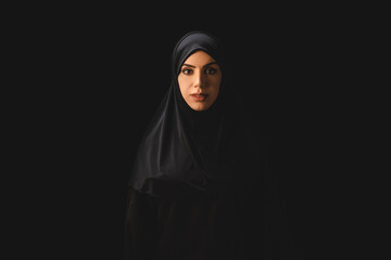 Beautiful muslim woman looking at camera isolated on black