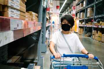 Asian woman wearing face mask selecting foods in supermarket to buy during coronavirus crisis or covid19 outbreak. Water supplies, grocery, prepare food, social distancing or new normal concepts