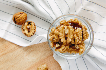 Walnut kernels lie in round bowl on kitchen table, close-up. View from above. Healthy lifestyle concept.
