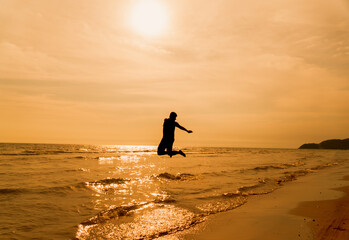 Fototapeta na wymiar Silhouette of man jump at the beach in sunset time