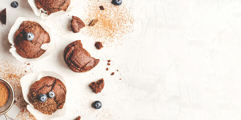 Homemade fresh chocolate muffins with berries and chocolate pieces. Top view.