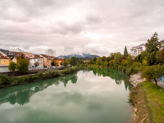 Homes and other buildings reflect in the calm waters of the Mur river