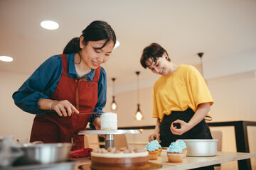 An Asian baker and a Caucasian baker making a mini cheesecake