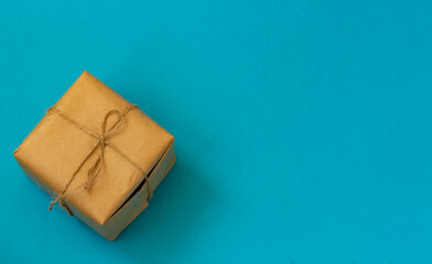 Craft paper wrapped gift box craft rope bow ribbon on a blue background, top view. Mockup for Father's Day celebration.