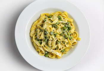 Tagliatelli con Limone e Piselli on white plate, Traditional italian pasta with lemon and peas.