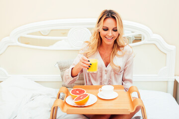 Obraz na płótnie Canvas young beauty blond woman having breakfast in bed early sunny morning, princess house interior room, healthy lifestyle concept
