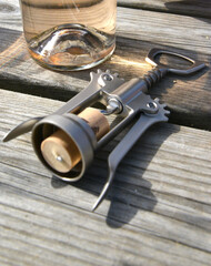 Steel bottle opener with cork still in in front of wine bottle