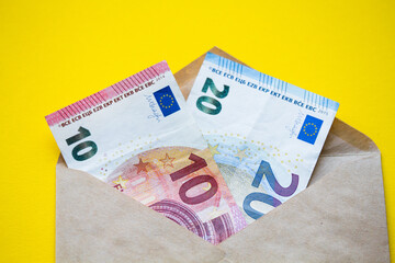 Euro banknotes in a white envelope on a wooden background. Cash savings