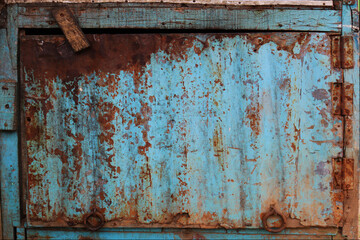 An old blue tin door with full of rust and cracks.