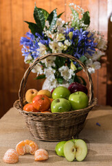 Canasta de fruta con flores naturales, sobre una mesa