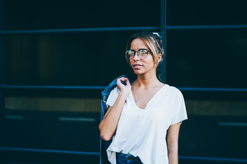 Young woman in optical eyeglasses walking in urban setting