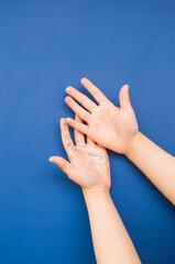 Child's hands with blue and silver color glitter and confetti on classic blue background.