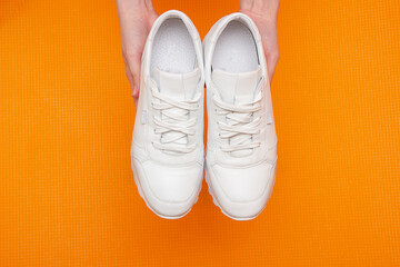 Fitness concept with white sneakers in hands, on a yellow background. view from above. Copy space