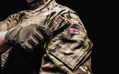 British soldier in camouflage shirt and tactical gloves on black background.