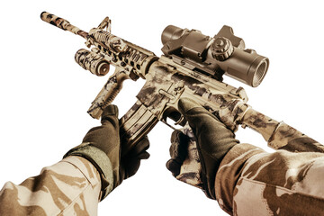 Soldier hands in desert camouflage uniform holding and reloading automatic rifle with scope first...