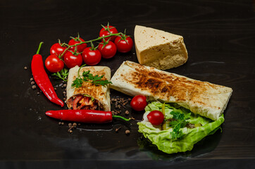 Shawarma cut with chicken meat on black background close-up. Cheese, red pepper parsley. Street Food, Fast Food, Oriental Food