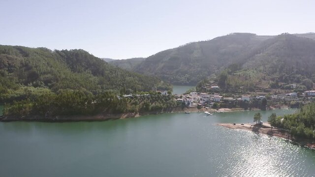 Aerial view of the mountain village of Dornes in Portugal. Drone footage of a picturesque village on a peninsula among a mountain river and green mountains.