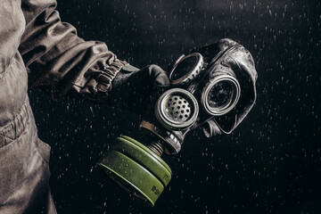 Stalker holding soviet rubber gas mask with filter on rain.