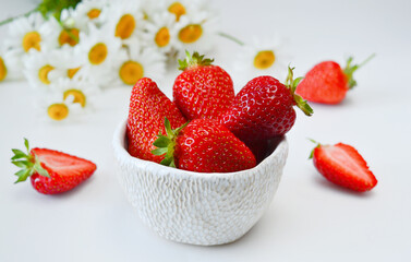 strawberries in a bowl isolated on white background and daisies