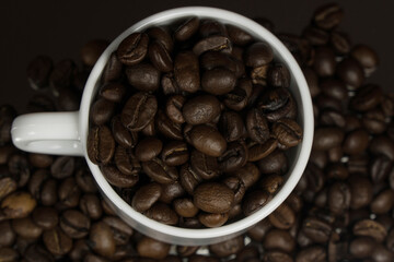 White mug with coffee grains sprinkled with coffee grains on a background