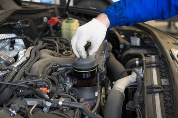 Car repair in a car service. Replacing an oil filter in a car engine. Hands of a professional mechanic holding an oil filter. Technical photo.