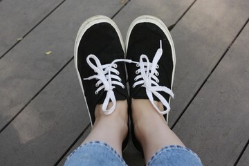Black sneakers with white laces on the feet