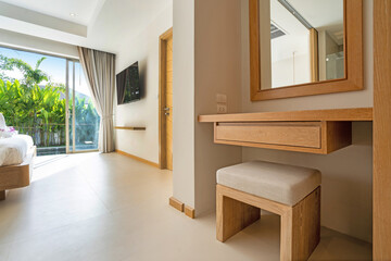 Interior design of dressing room in luxury villa feature stool, dressing table, mirror, bed, television, and sliding door with view