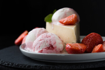  ice cream scoops with slice of cheesecake with strawberry and mint decoration. Summer food concept with copy space.