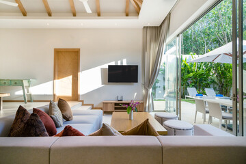 Interior and exterior design of living room with pool view in luxury pool villa feature television,...