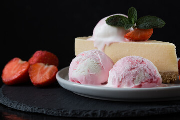  ice cream scoops with slice of cheesecake with strawberry and mint decoration. Summer food concept with copy space.