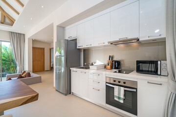 Interior design of kitchen in luxury villa, apartment feature wooden dining table, kitchen counter, refrigeratpr, oven, hood and microwave