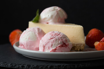  ice cream scoops with slice of cheesecake with strawberry and mint decoration. Summer food concept with copy space.