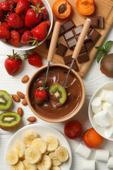 Composition with ingredients for chocolate fondue on white wooden background. Cooking fondue