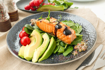 Close-up of grilled salmon fillet with green bean sprouts with avocado on a plate. Dietary food in case of involuntary quarantine