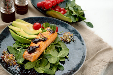 Close-up of grilled salmon fillet with green bean sprouts with avocado on a plate. Dietary food in case of involuntary quarantine