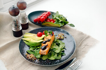 Close-up of grilled salmon fillet with green bean sprouts with avocado on a plate. Dietary food in case of involuntary quarantine