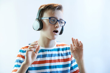 Funny boy teenager listens to music on headphones and dances