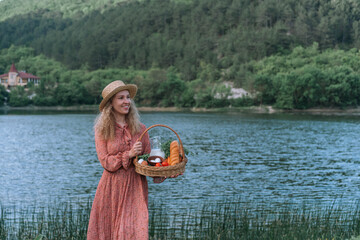 Woman farmer on the background of the lake with a basket in which homemade products.