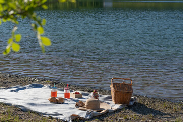 Picnic with a basket and glasses with juice on the lake.