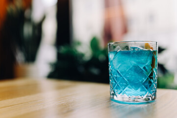 Blue colored citrus alcohol cocktail on a table in a restaurant in a glass glass