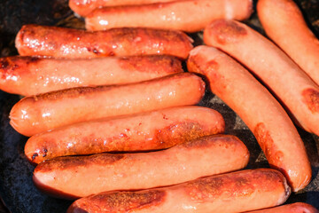 Delicious grilled barbecue sausages in an old cast-iron pan . The process of cooking sausages in a pan