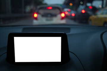Display of GPS or navigator device in a holder in car with blur background of traffic jams in the evening. Mockup white empty screen for text, copy space
