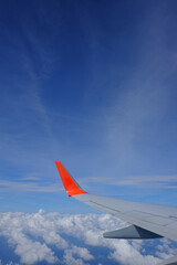 Fototapeta premium Wing of airplane with beautiful blue sky and clouds from airplane window, traveling to oversea